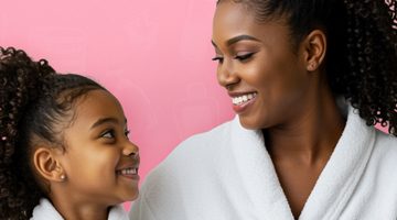 Girl and woman in white spa robes smiling at each other against a pink background, promoting kids' Nail Art treatment